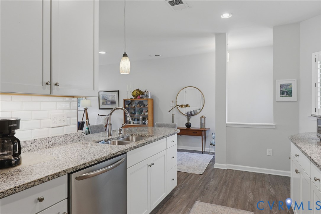 Kitchen featuring light-toned cabinetry, a stainless steel dishwasher, a double basin sink with a high-arc faucet, and granite countertops
