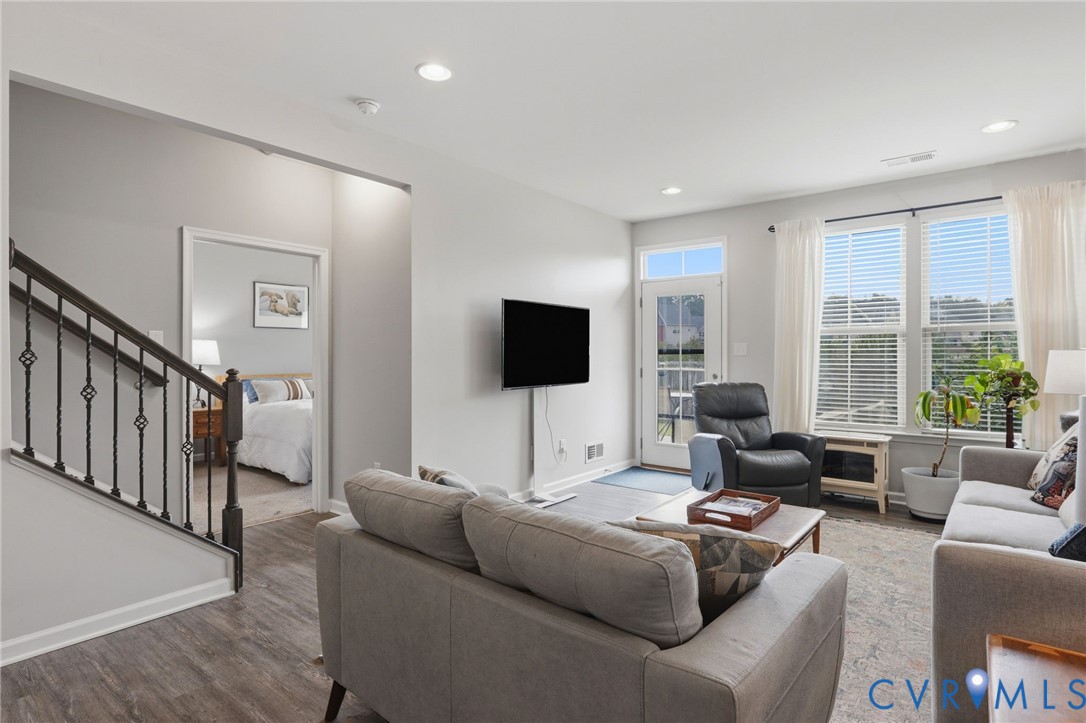 Spacious living area featuring wood-finish flooring, recessed lighting, and a neutral color palette