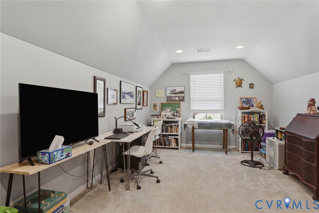 Spacious room featuring vaulted ceilings, recessed lighting, and light-toned carpeting