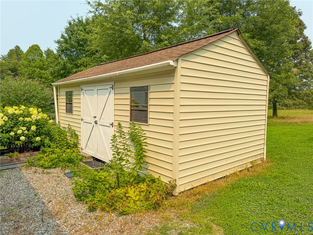 Detached storage shed featuring horizontal siding, a gabled roof, and two operational windows