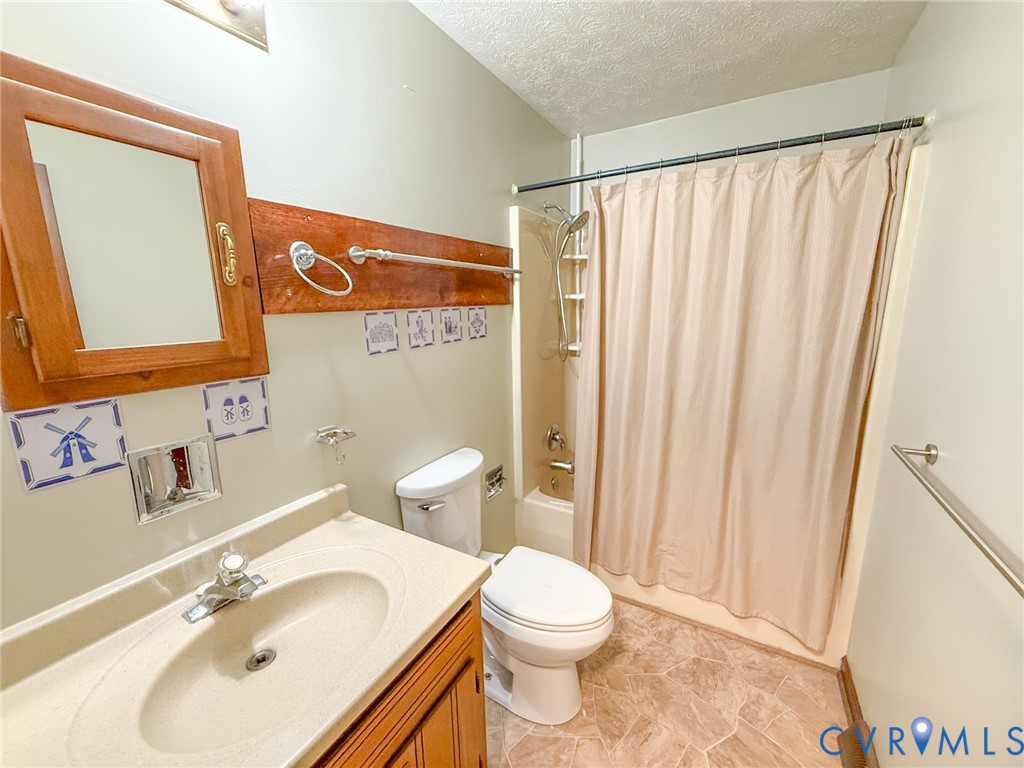 Bathroom featuring a single vanity with an integrated sink, a built-in medicine cabinet with a mirror, a toilet, a shower-tub combination, and patterned floor tiling