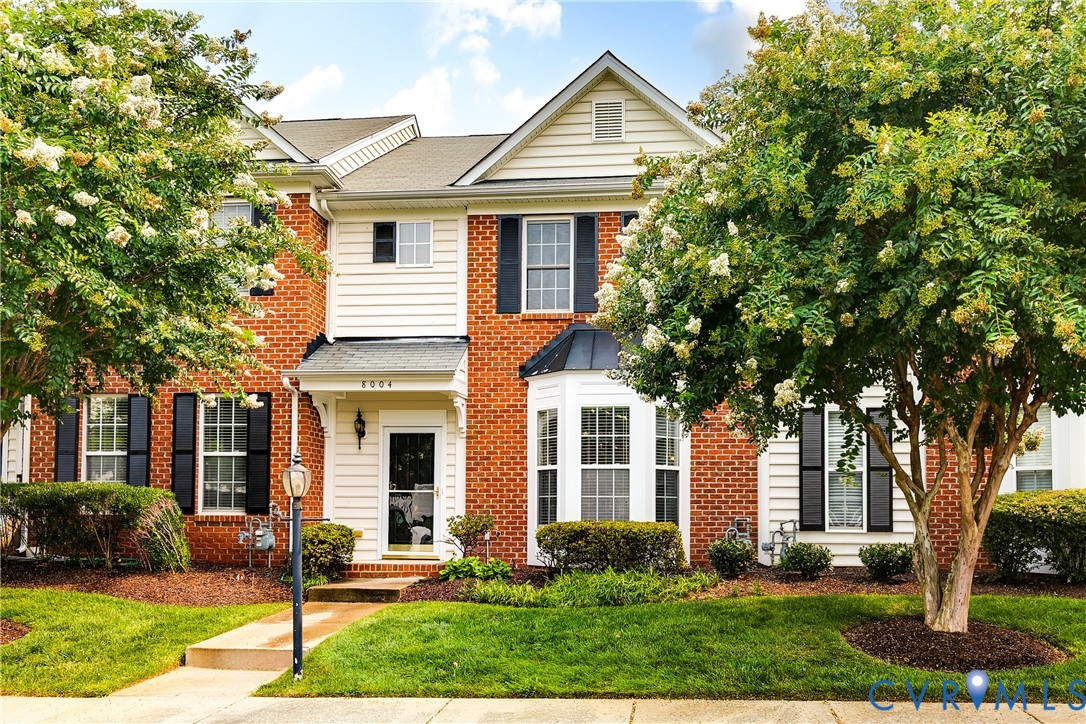 Brick and siding exterior featuring a covered entry, decorative bay window, and black louvered shutters