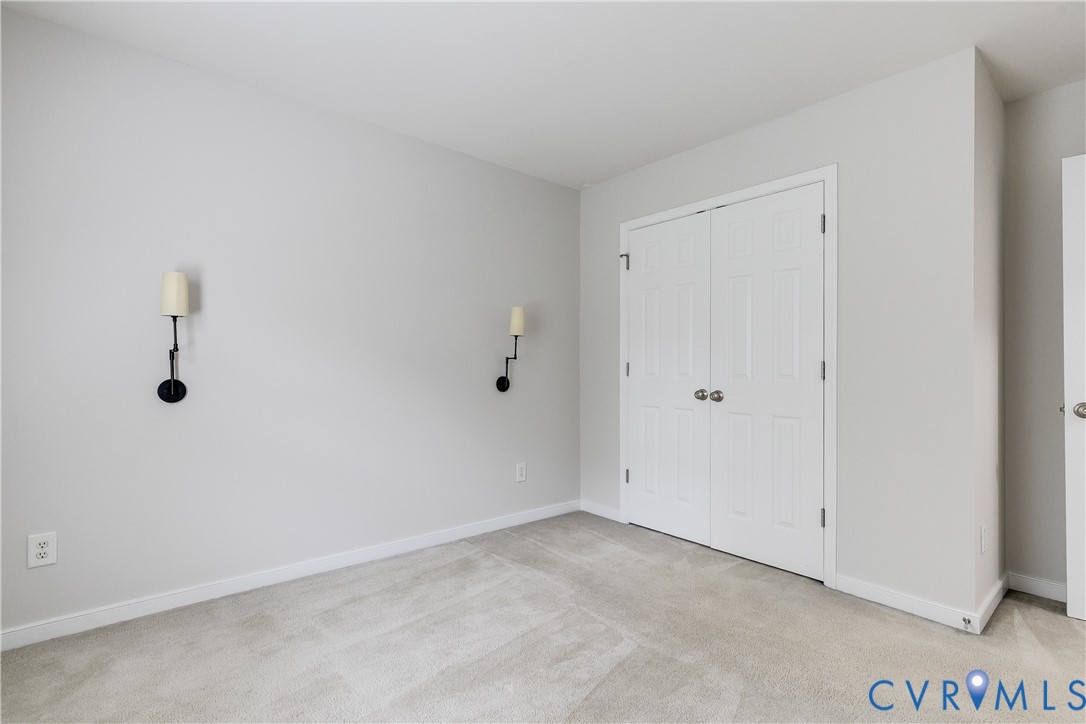 Neutral wall paint with white trim, light gray carpeting, and bifold closet doors