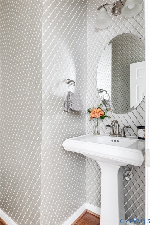Pedestal sink with brushed nickel faucet, an oval mirror, and a two-light vanity fixture