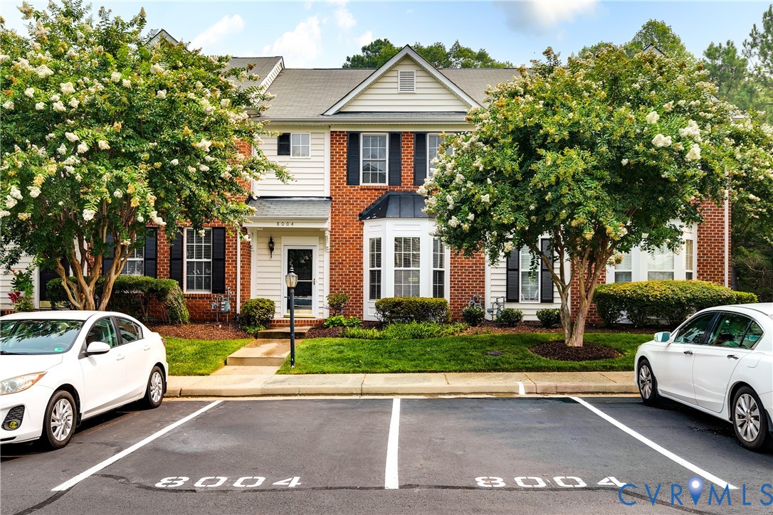 Townhome exterior featuring a brick and siding facade, bay window, and black louvered shutters