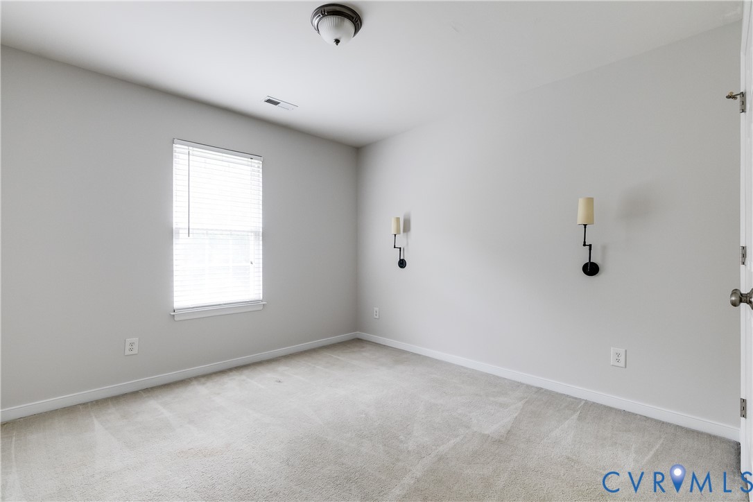 Carpeted room with a central window featuring horizontal blinds