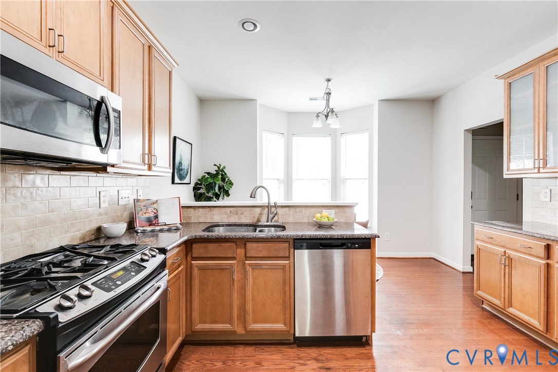 Kitchen featuring stainless steel appliances, wood-finish flooring, recessed lighting, bay windows, and light wood cabinetry