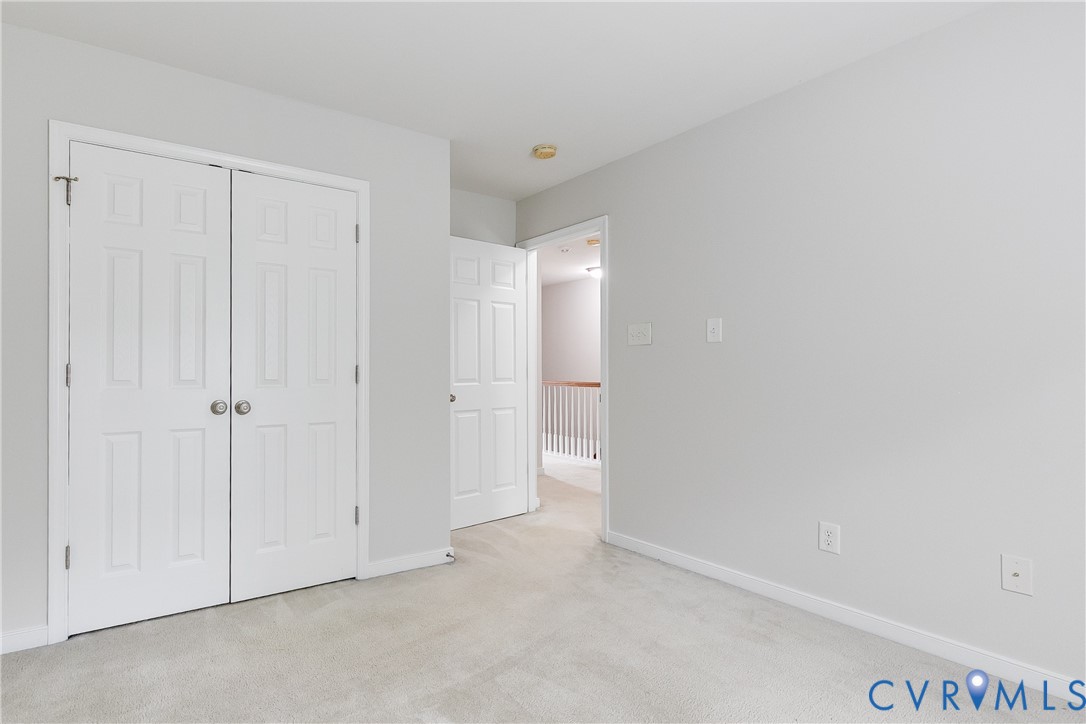 Carpeted interior space with light gray walls, white baseboards, and a white six-panel bifold closet door