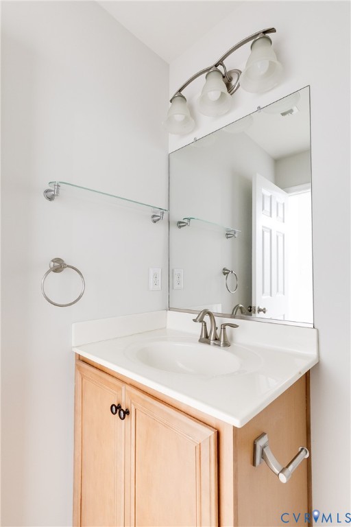 Bathroom vanity featuring a single basin sink, light-toned cabinetry, and a rectangular mirror