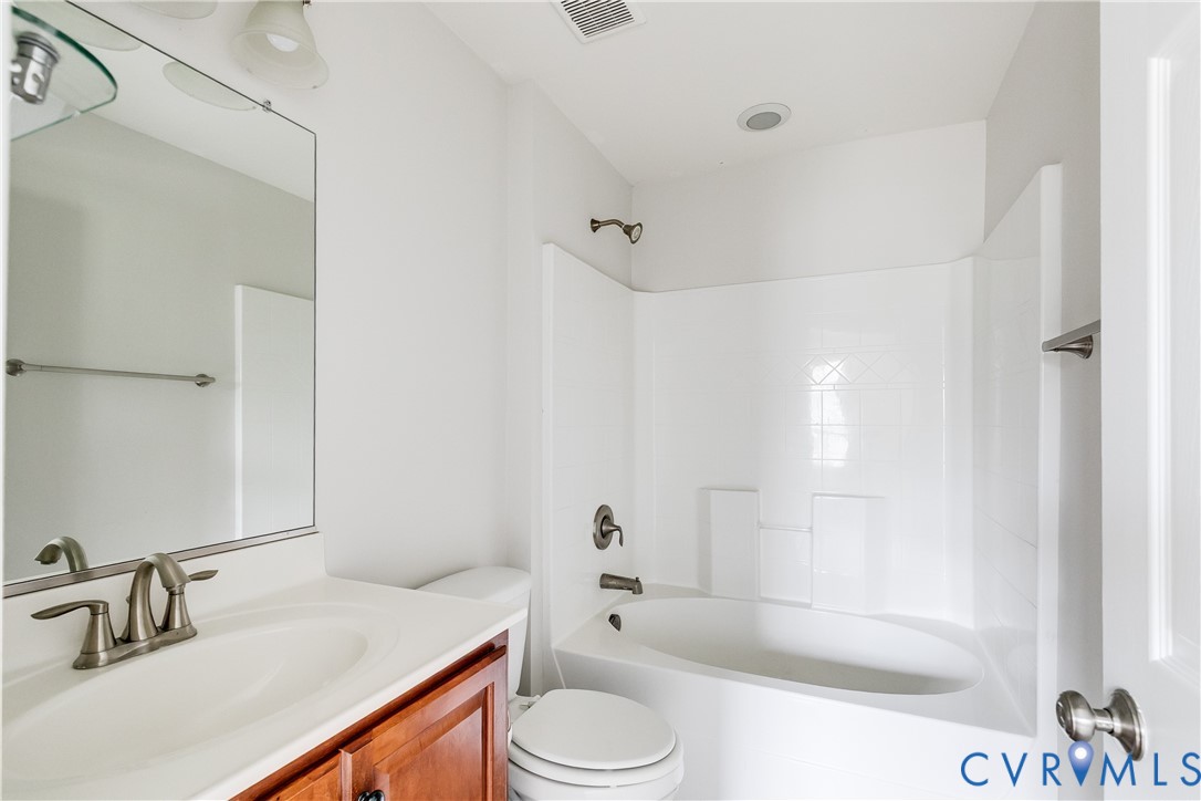 Bathroom featuring a white ceramic bathtub with shower, white tile surround, and brushed nickel fixtures