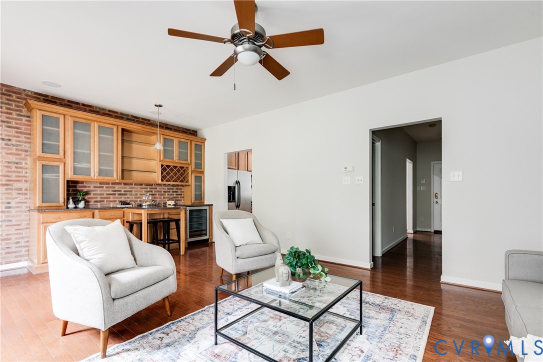 Built-in bar area featuring brick detailing, wood cabinetry with glass fronts, and a beverage cooler