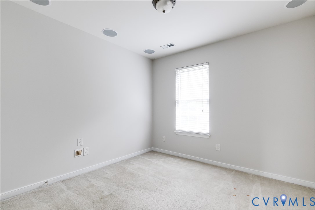 Neutral wall paint complementing light-toned carpeting, with a window featuring horizontal blinds