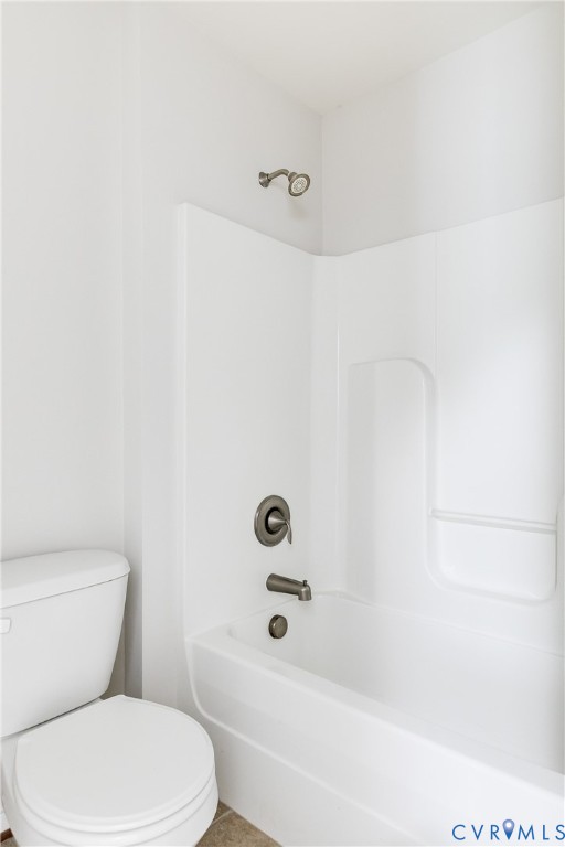 White bathtub with integrated shower, dark bronze fixtures, and an adjacent white toilet
