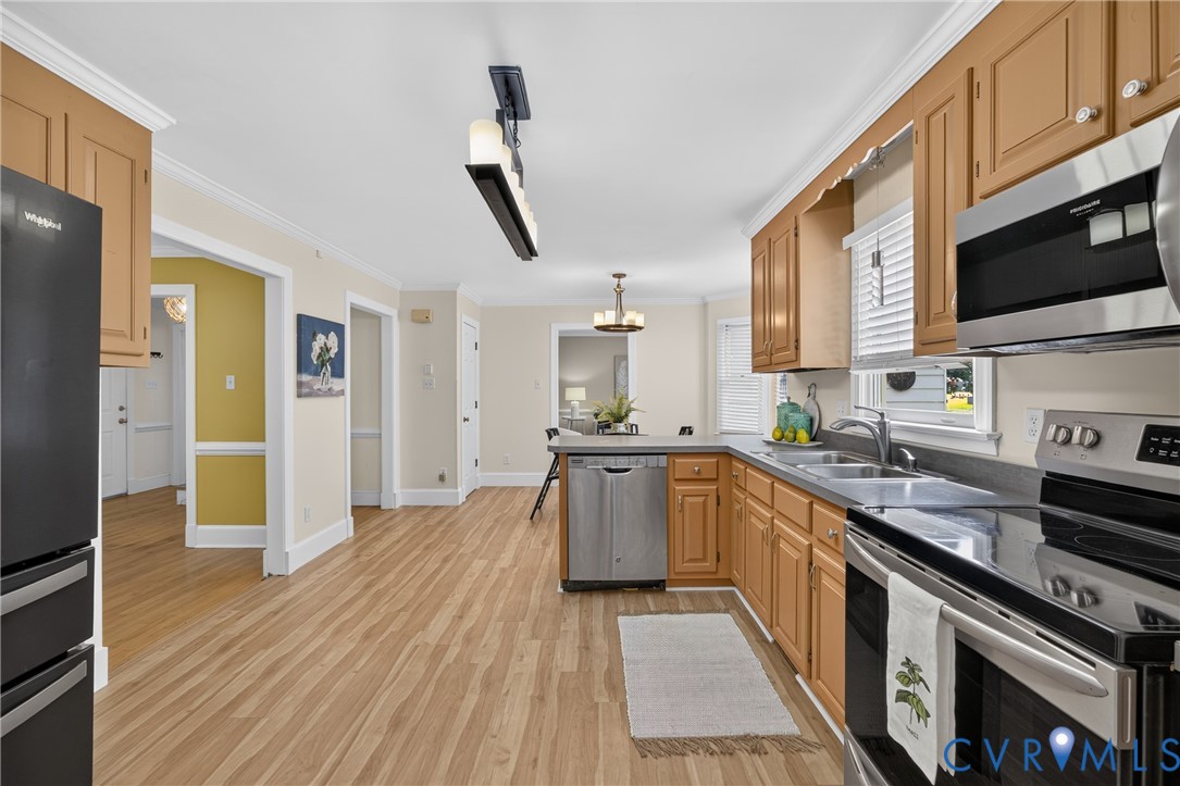 Kitchen featuring wood-finish flooring, stainless steel appliances, wood cabinetry, and recessed lighting