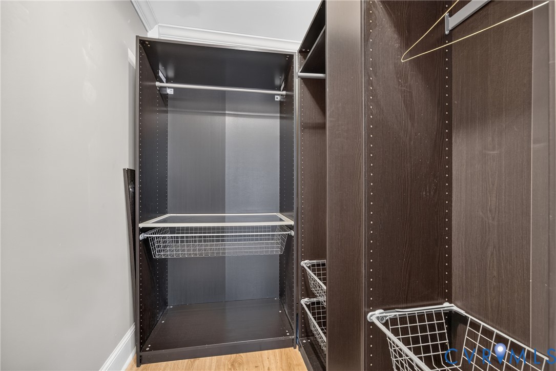 Custom closet system featuring dark wood-finish cabinetry, adjustable shelving, and integrated wire baskets