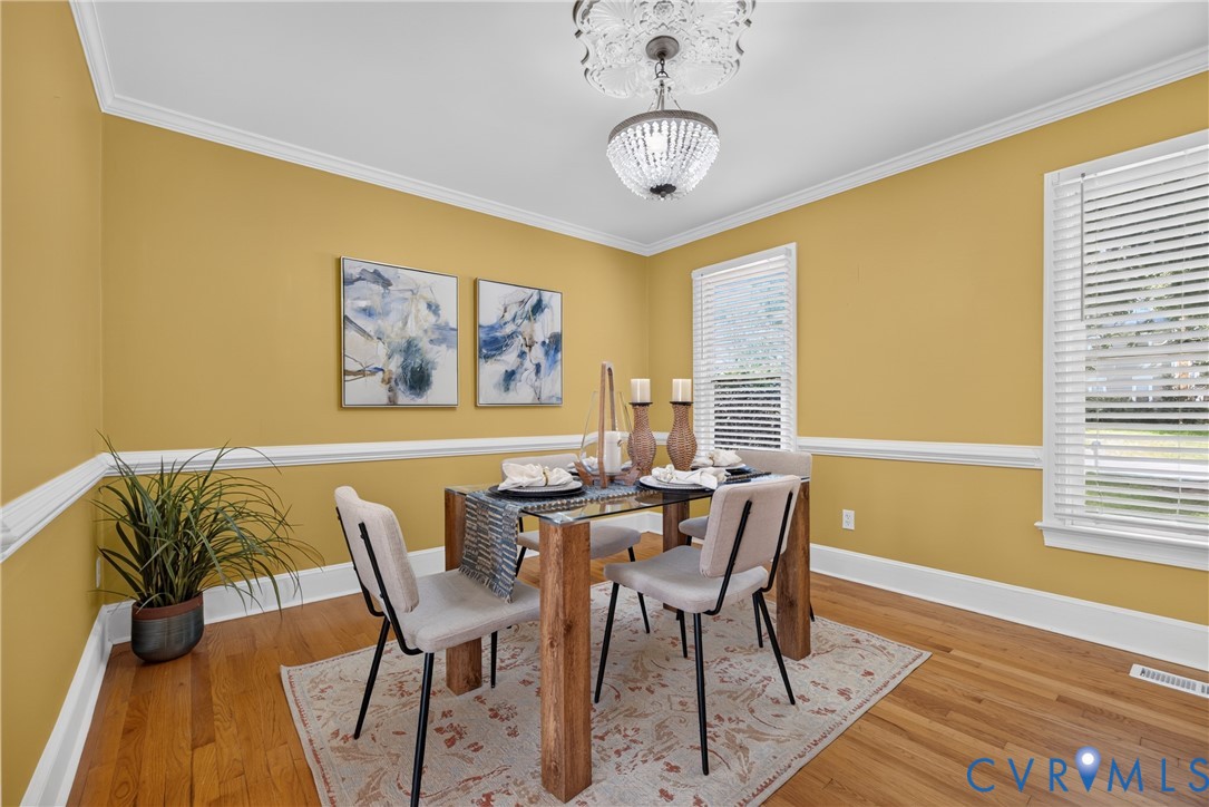 Hardwood flooring, crown molding, chair rail molding, two windows, and a ceiling light fixture