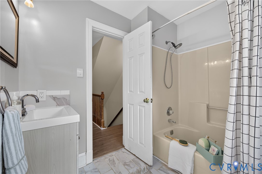 White integral sink with polished chrome faucet, light wood-finish vanity, and gray wall tile backsplash