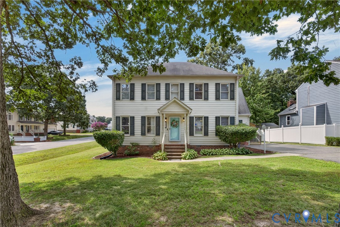 Two-story colonial-style residence featuring white siding, dark shutters, and a welcoming light blue front door
