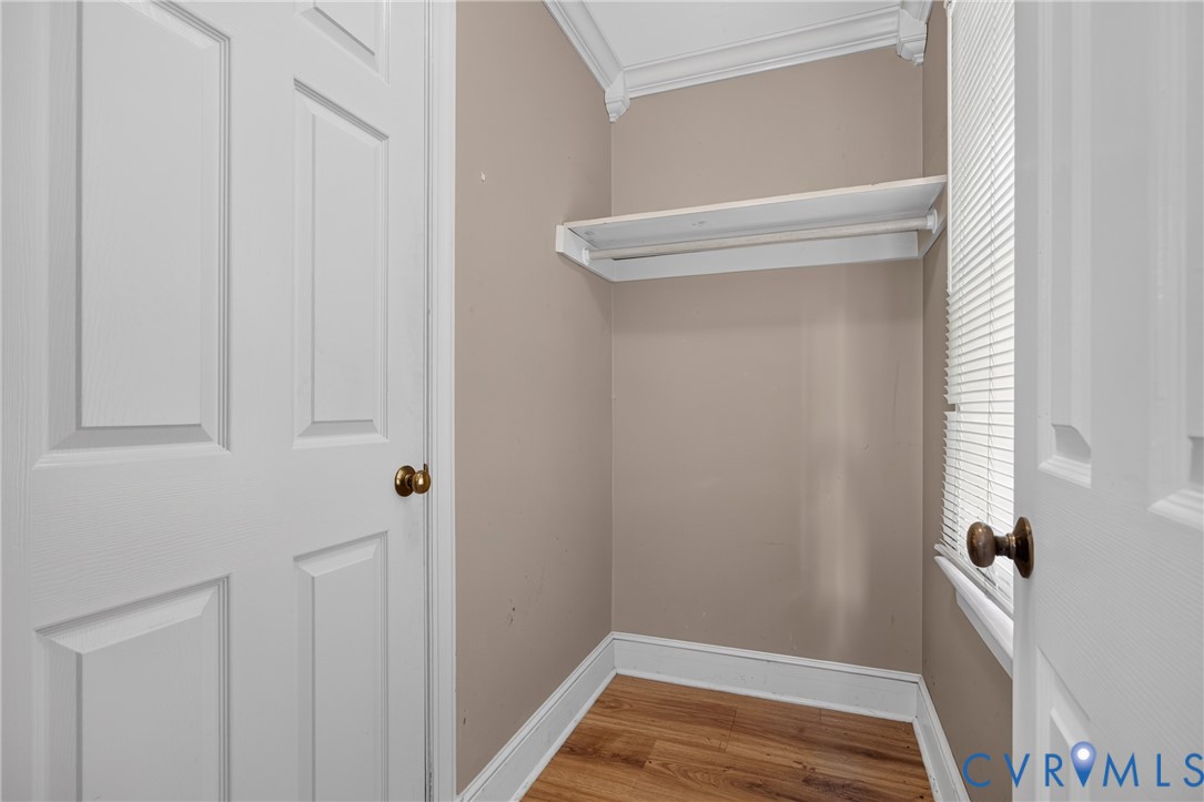 Built-in shelving with hanging rod, wood-finish flooring, and white trim