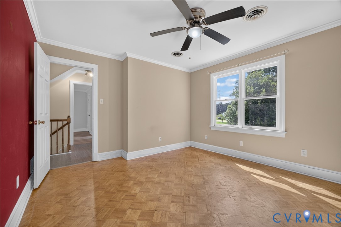 Room featuring wood parquet flooring, crown molding, a ceiling fan with integrated lighting, and a large window with white trim