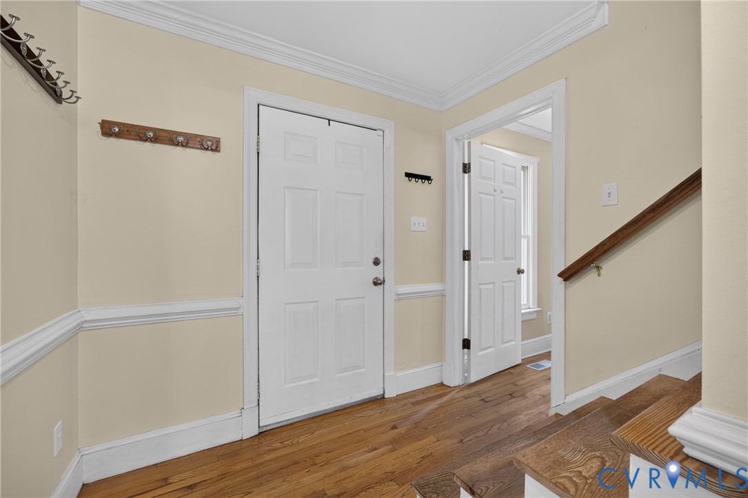 Wood-finish flooring, white paneled doors, and crown molding