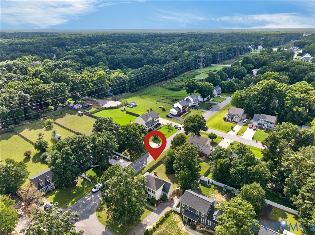 Aerial view showcasing a substantial residential property set on expansive grounds with mature landscaping, manicured lawn, and tree-lined perimeter
