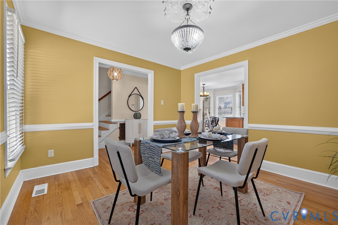 Hardwood flooring, crown molding, chair rail molding, and a crystal-beaded chandelier