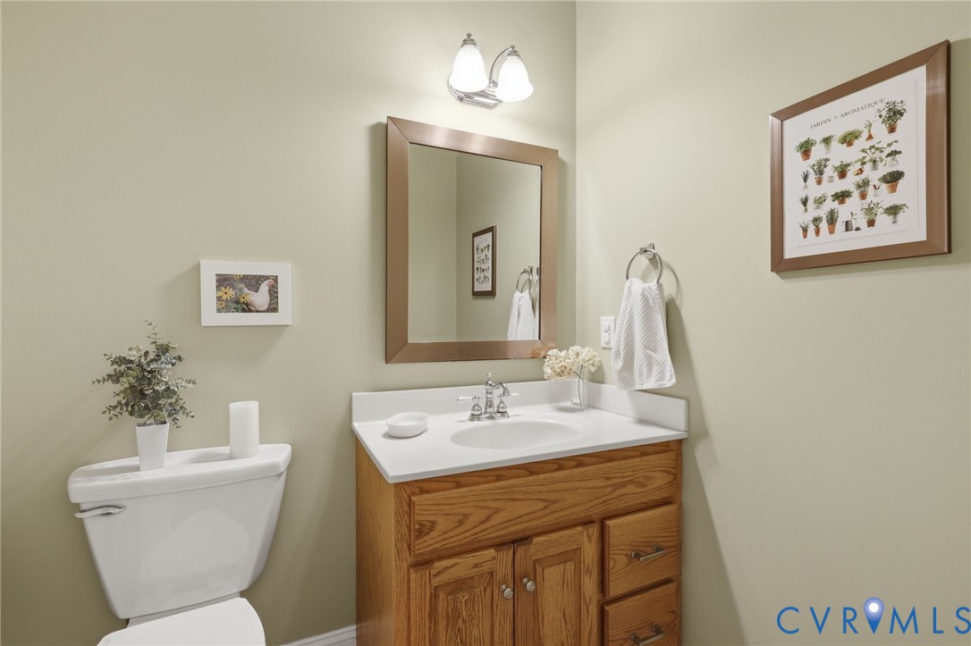 Powder room featuring a single vanity with wood-finish cabinetry, a white countertop, and a chrome faucet