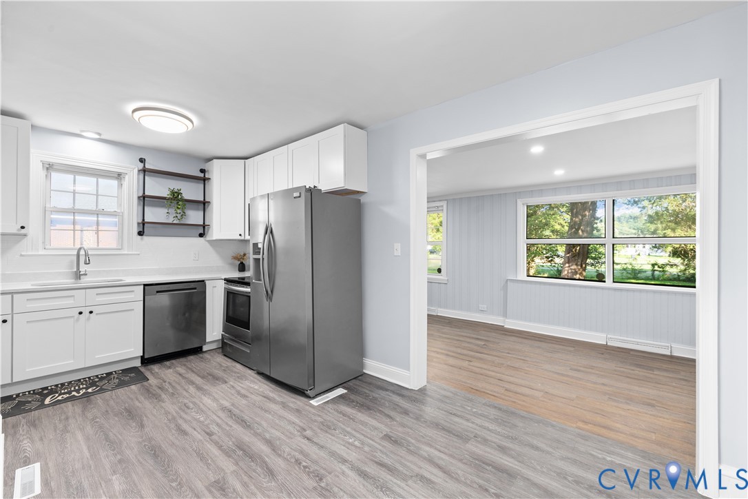 Updated kitchen featuring white shaker cabinetry, stainless steel appliances, and wood-finish flooring Updated kitchen featuring white shaker cabinetry, stainless steel appliances, and wood-finish flooring