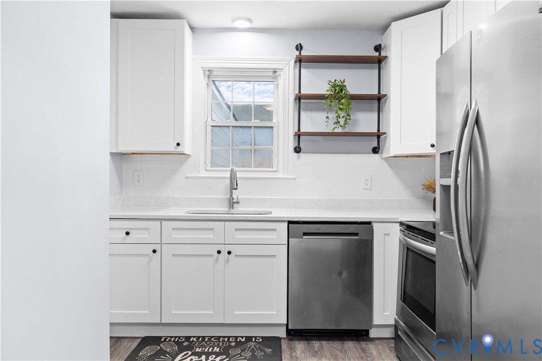 White shaker cabinetry, quartz countertops, stainless steel appliances, subway tile backsplash, and wood-finish flooring White shaker cabinetry, quartz countertops, stainless steel appliances, subway tile backsplash, and wood-finish flooring