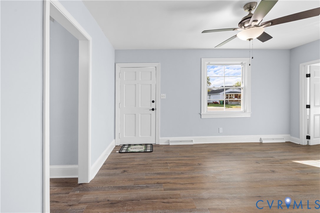 Wood-finish flooring, white trim, light wall color, ceiling fan with light, and a paneled door