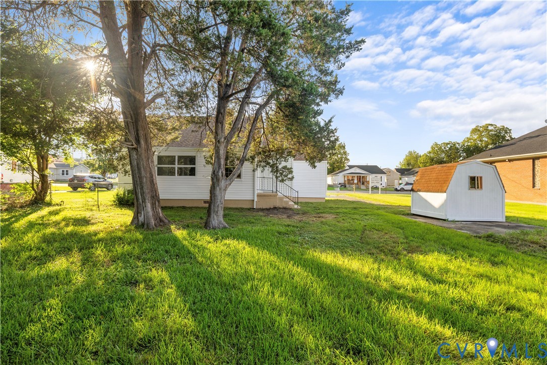Expansive lawn with mature trees and a detached storage shed