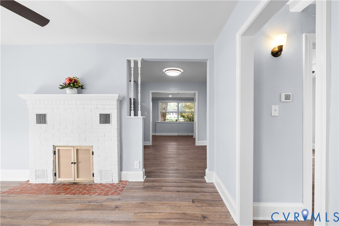 Whitewashed brick fireplace with a brick hearth, wood-finish flooring, and a ceiling fan Whitewashed brick fireplace with a brick hearth, wood-finish flooring, and a ceiling fan