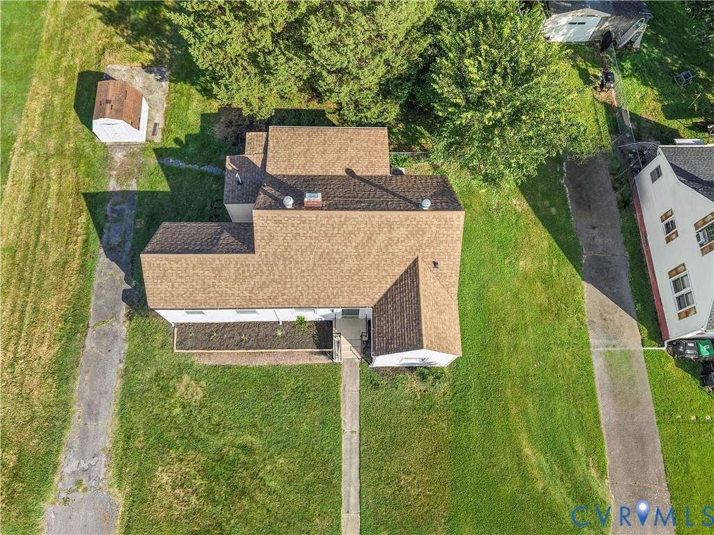 Gable roofline with asphalt shingles, concrete pathway, and an additional shed structure