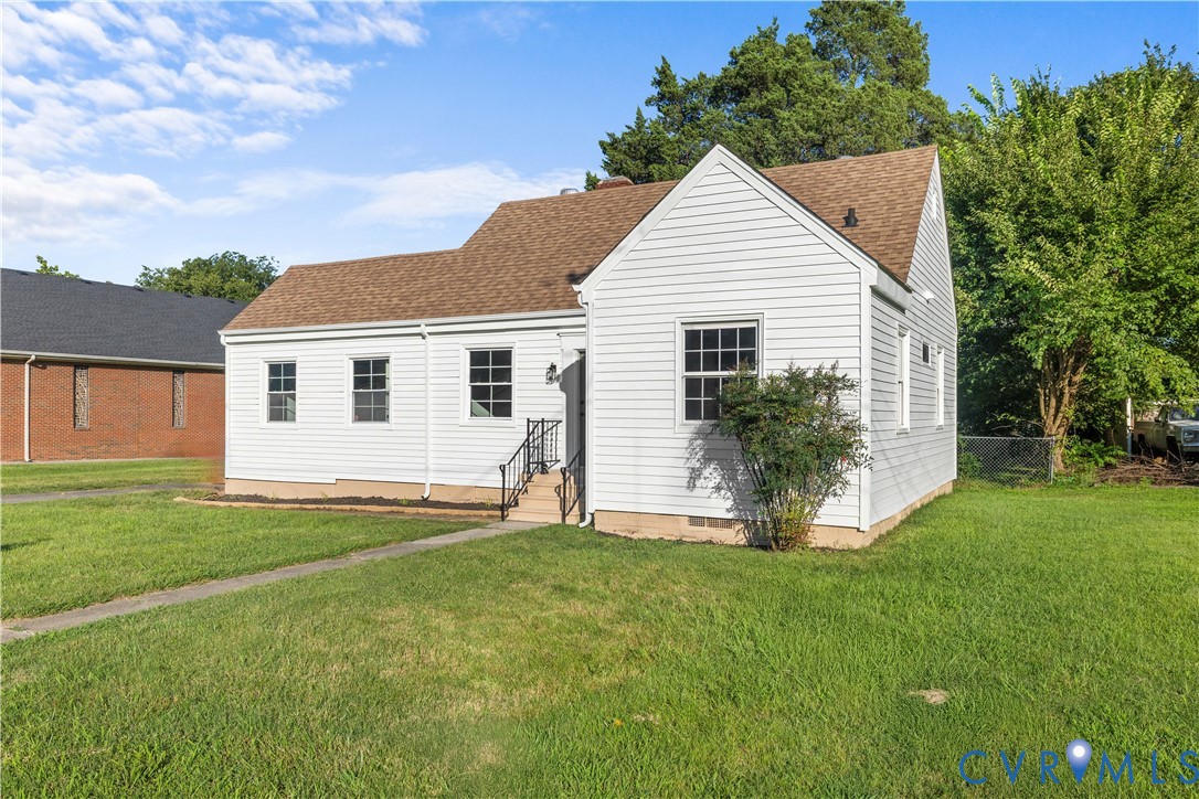 White siding exterior with a brown shingle roof, featuring multiple windows, a front entry, and a paved walkway