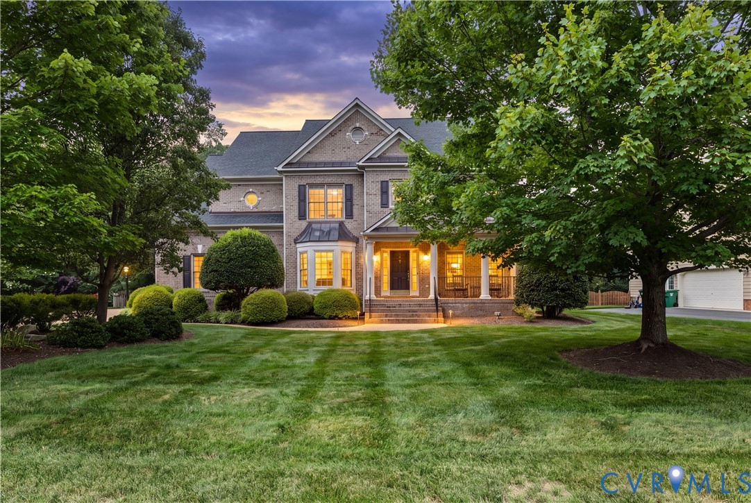 Multi-level brick exterior featuring a covered front porch, bay window, architectural roof shingles, and mature landscaping Multi-level brick exterior featuring a covered front porch, bay window, architectural roof shingles, and mature landscaping