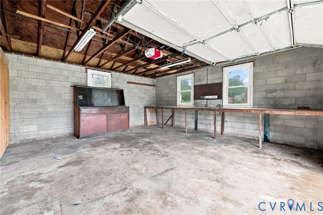 Concrete block walls with two windows, exposed ceiling beams, and a concrete floor