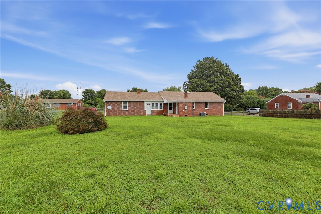 Expansive lawn area with mature landscaping and brick exterior