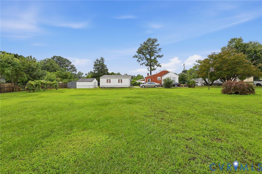 Expansive green space featuring a large grassy area, a detached storage shed, and a privacy fence