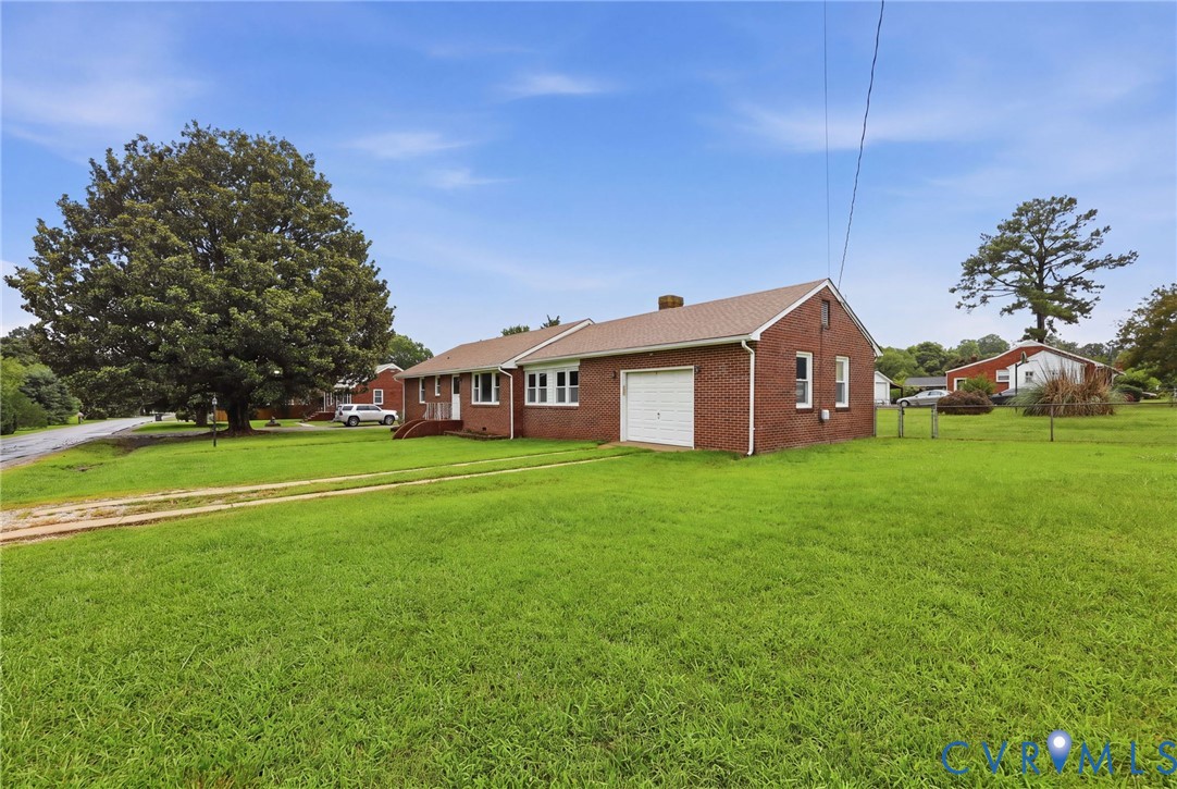 Brick ranch home situated on expansive manicured grounds featuring mature shade trees, a detached garage with overhead door, and ample green lawn space