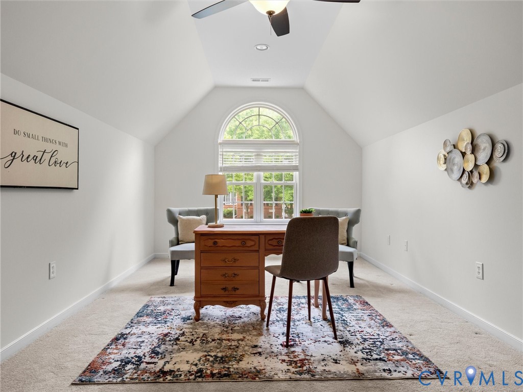 Vaulted ceiling with ceiling fan, arched window with blinds, and light-colored carpeting