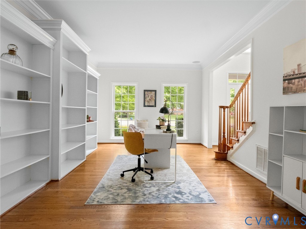 Hardwood flooring throughout, built-in shelving, white trim, and a wood staircase with balusters