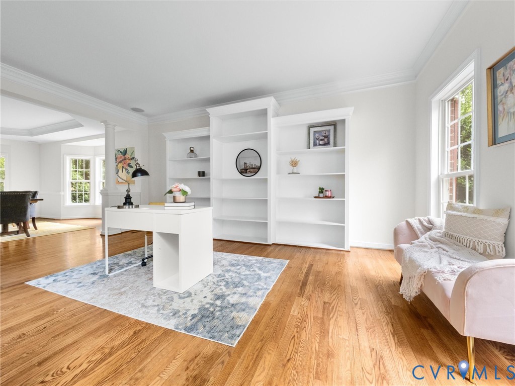 Hardwood flooring throughout, built-in shelving, crown molding, and large windows with natural light