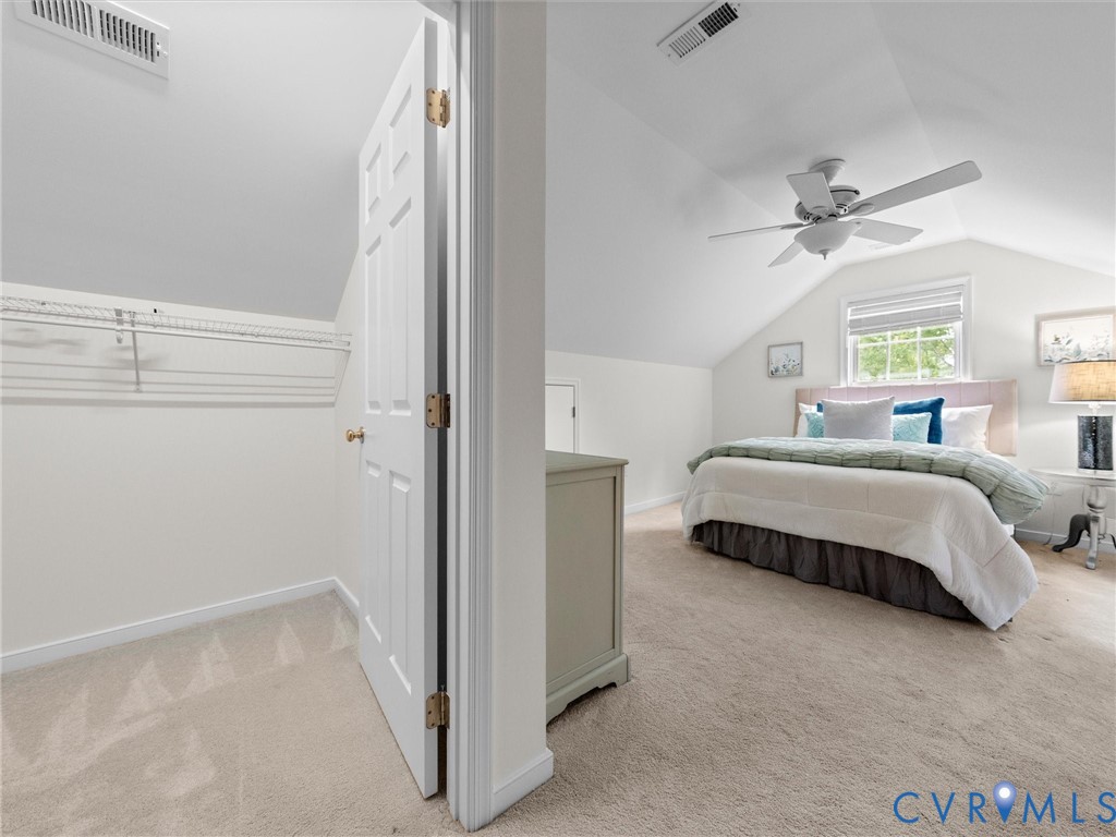 Sloped ceiling bedroom featuring a ceiling fan, window with blinds, and light-toned carpeting