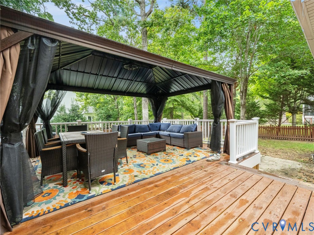 Spacious exterior deck featuring a dark metal gazebo, privacy curtains, and white railings