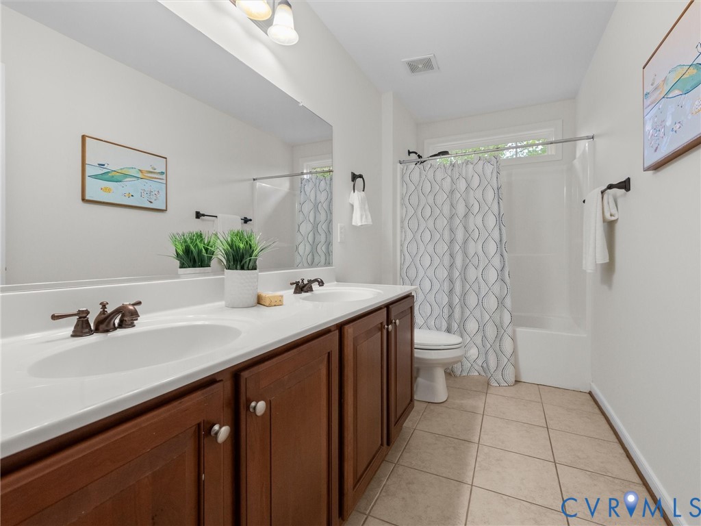 Double vanity with white countertop, integrated sinks, and bronze-finish fixtures
