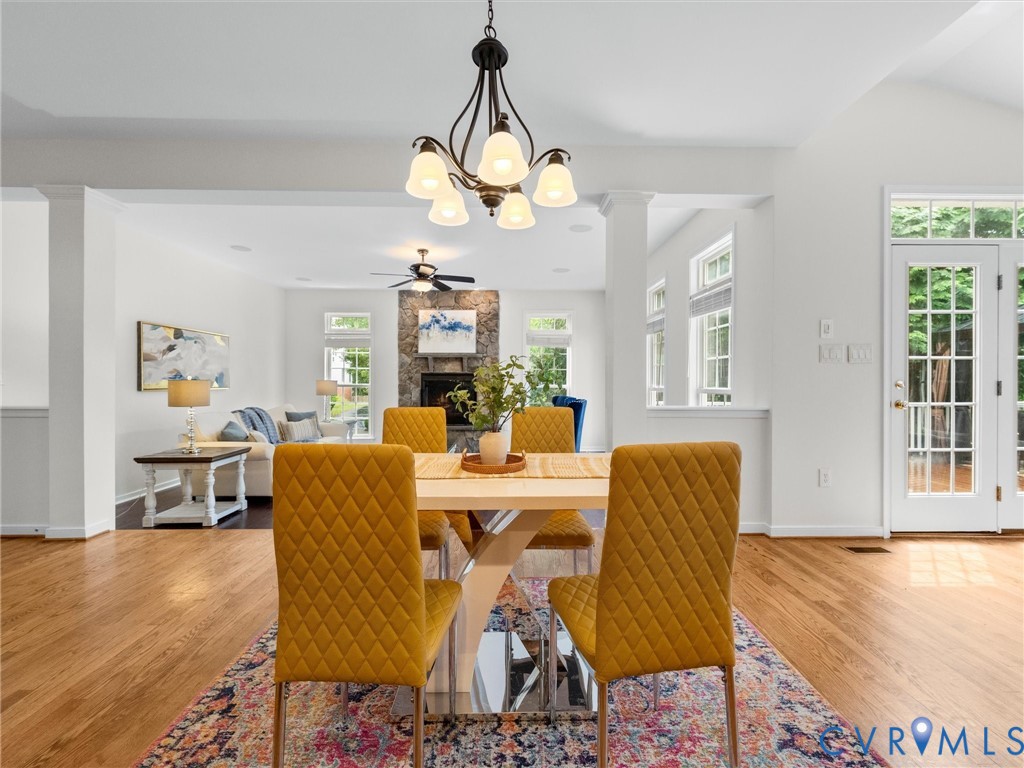Hardwood flooring, elegant chandelier, French doors, recessed lighting, and a stone-clad fireplace