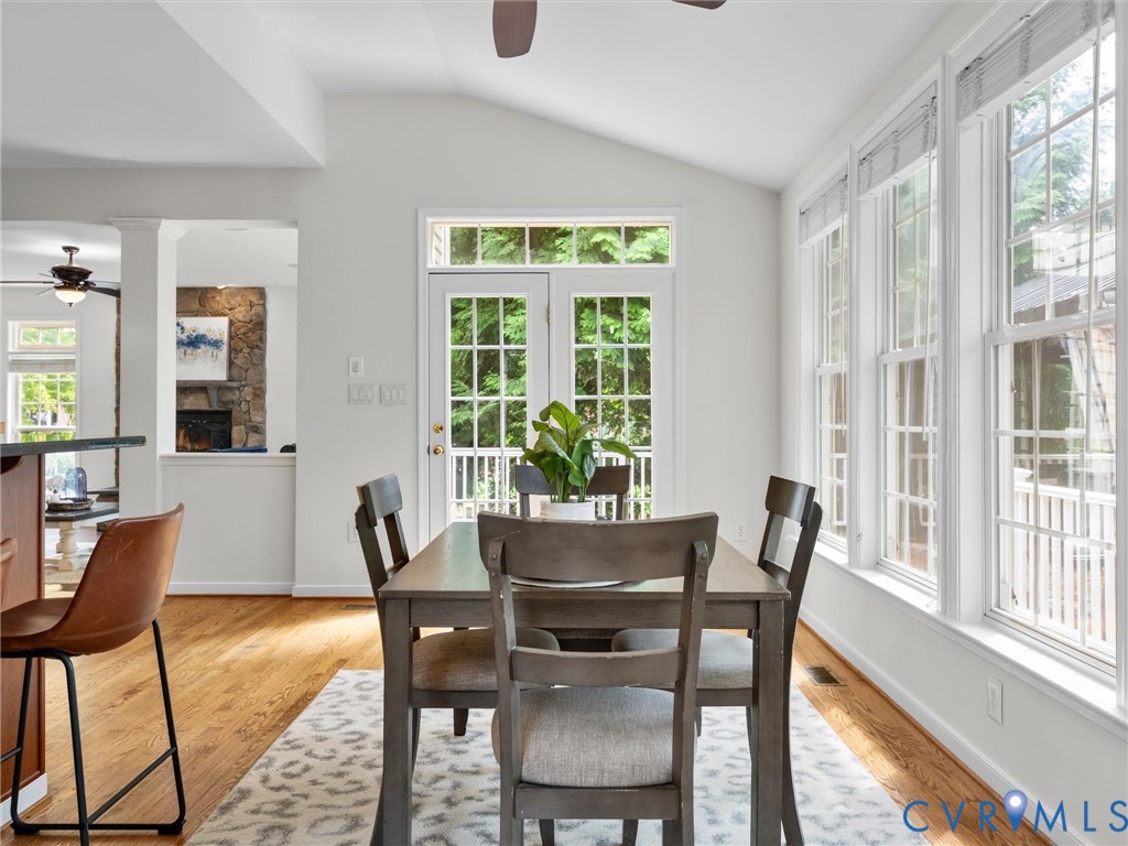 Vaulted ceiling, multiple windows, French doors, wood-finish flooring, and a stone-clad fireplace