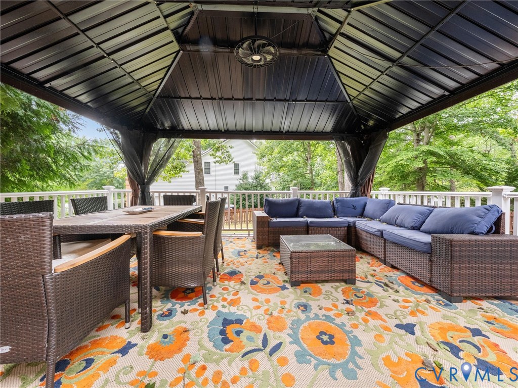Covered outdoor deck featuring a metal gazebo, white railing, and a ceiling fan