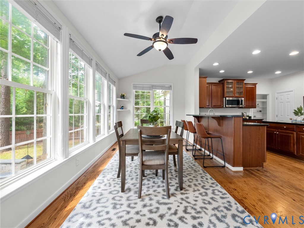 Spacious dining area with extensive window array, vaulted ceiling, and a ceiling fan
